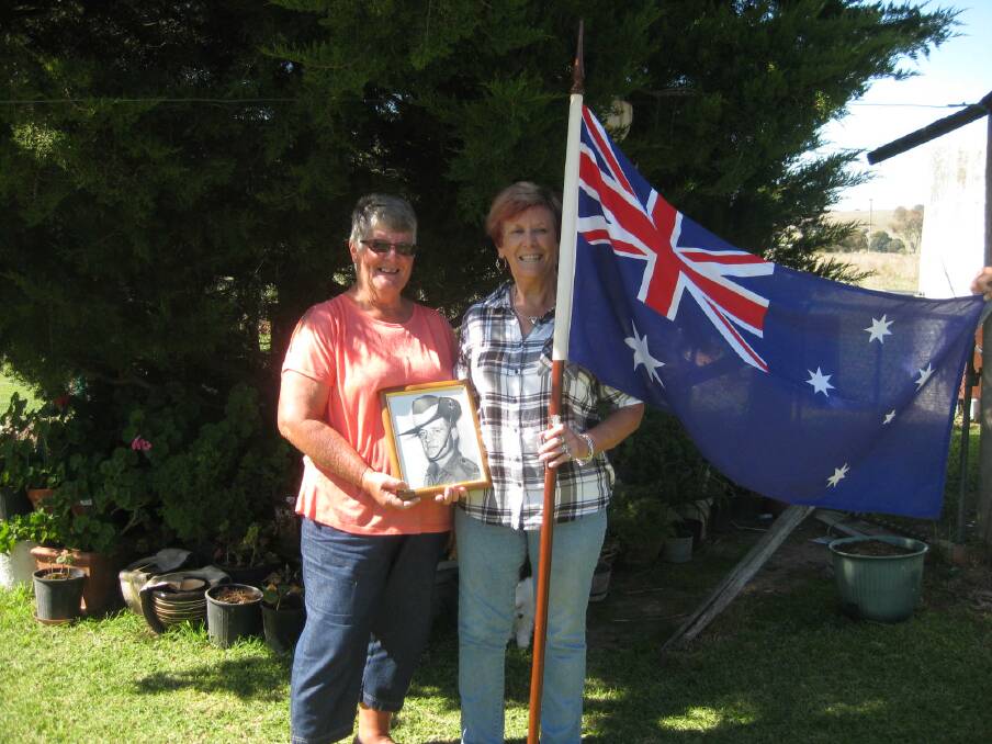 REMEMBERING: Two of Private Barry Thompson's sisters, Valda Lees and Helen Keed, with his official photo and the flag with his name that was carried in the Welcome Home March. Photo: supplied