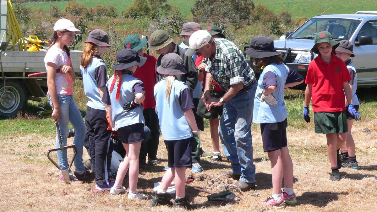 GROWING: Roslyn Landcare Group project coordinator Eric Hurn, showing the children how it's done at a past tree planting