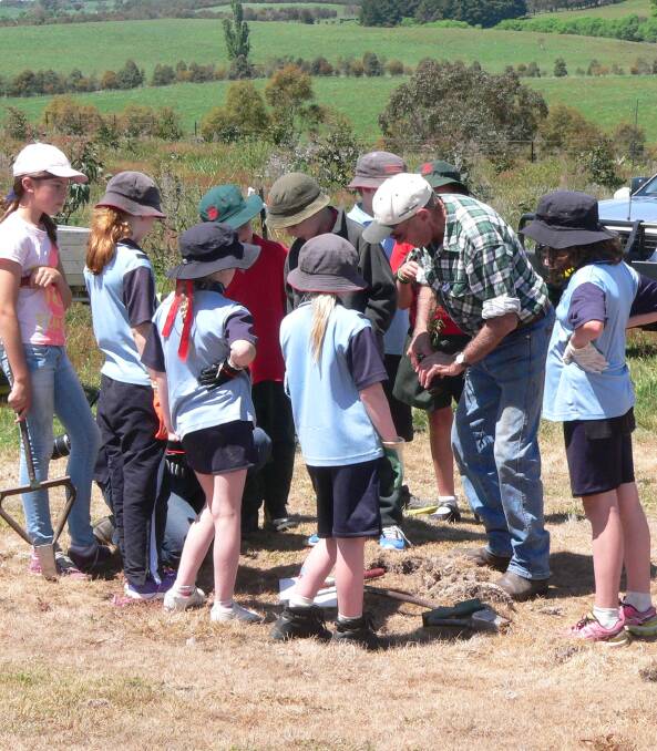 Roslyn Landcare Group project coordinator Eric Hurn, showing the children how it's done at a past tree planting day