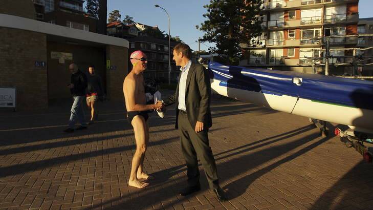 A local swimmer congratulates Mike Baird at Manly beach on his first day as Premier. Photo: Kate Geraghty