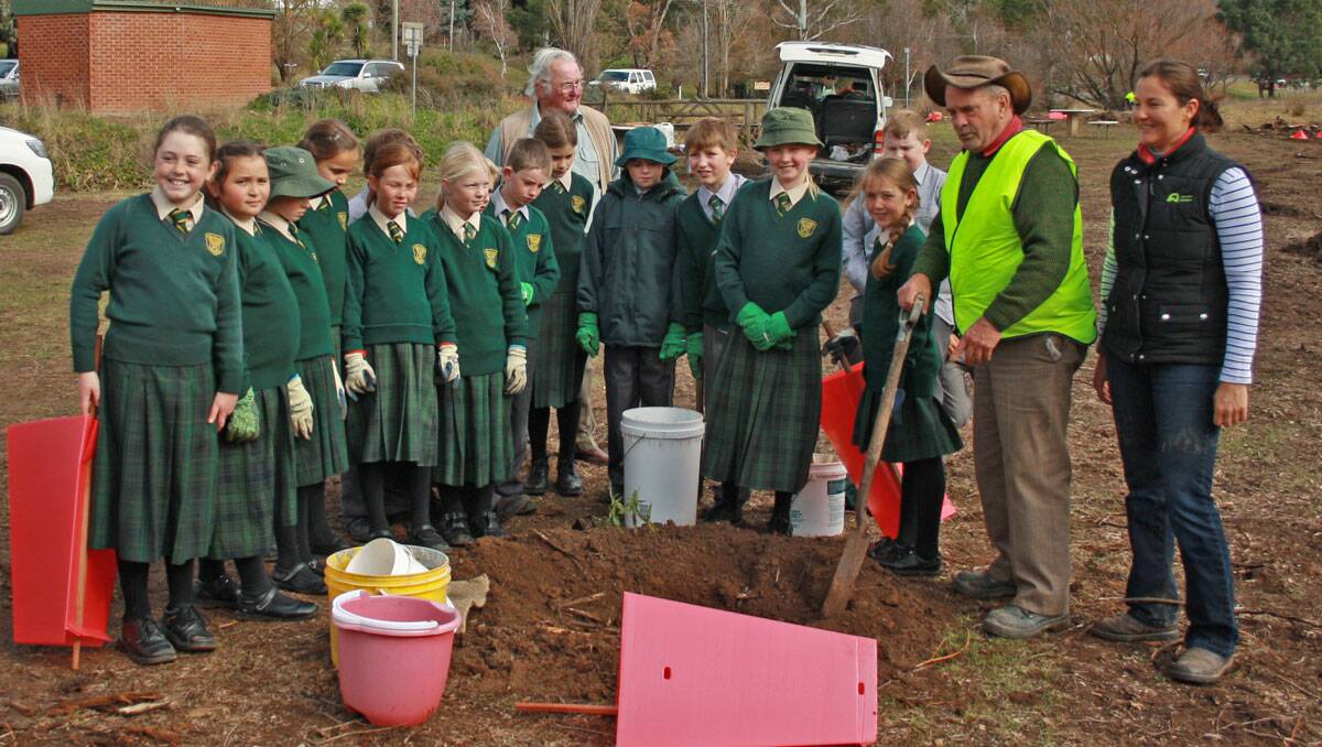 The St Mary’s school children being shown the finer details on how to plant a tree by ‘big people helpers’, (behind) Councillor Malcolm Barlow, (far right) Barry Murphy and Upper Lachlan Landcare representative Mary Bonet. Children (left to right) Emily Secombe, Misha O’Brien, Georgia Anderson, Tori Williams-Langdon, Meg Gamble, Sam Spackman, Alex Slattery,Paddy Lowe, Liam Croke, Kiara Storrier, Daniel O’Brien, Harrison Hayes, Grace Abbey, Richard Branson and Alexis Bugeja