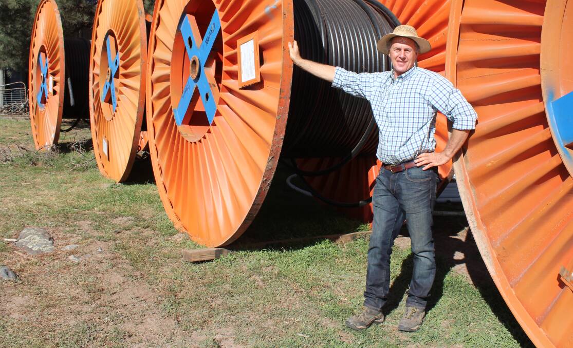 Crookwell farmer Charlie Prell stands next to electrical wires as part of the Crookwell 2 project on his farm. 
