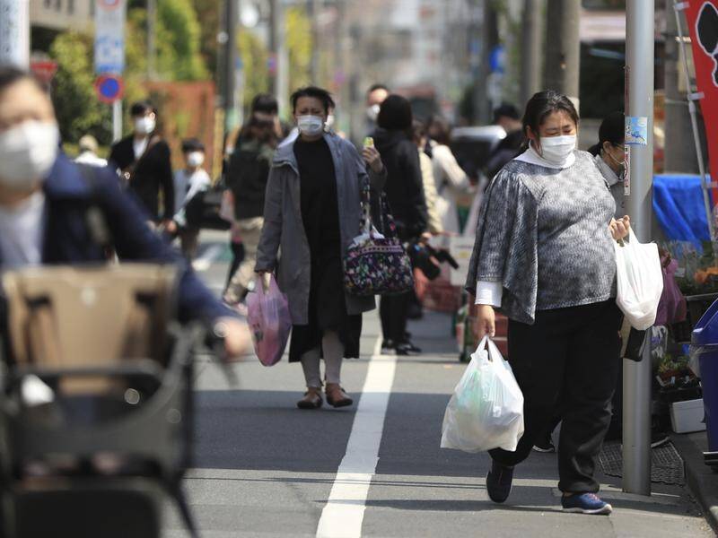 People with face masks shop in Tokyo one day after the government declared a state of emergency.