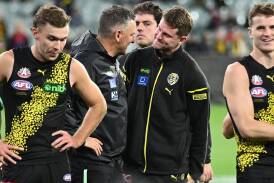Richmond coach Adem Yze (second left) chats with an injured Jacob Hopper during the Melbourne game. (James Ross/AAP PHOTOS)