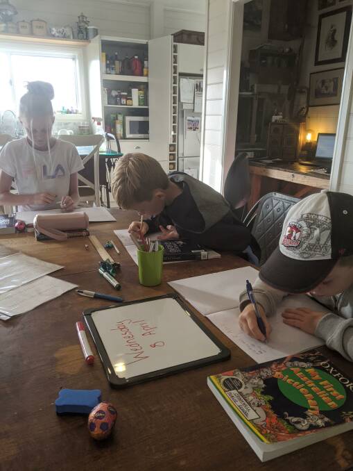 Betsy, George and Charles Willis practise spelling in their lounge room. Photo: supplied