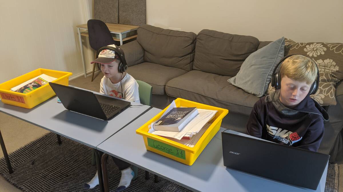 Charles and George Willis read books online using the two desks their school lent them. Photo: supplied