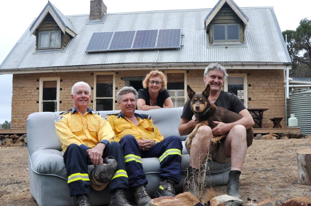 ABC journalist Richard Glover with wife Debra Oswald (right) sit on a thrown out couch that has provided firefighters with relief in front of their Tallygang Mountain Road weekender. Pictured with Taralga Rural Fire Brigade Captain John Sullivan and member Peter Davies. Photo: Hannah Sparks