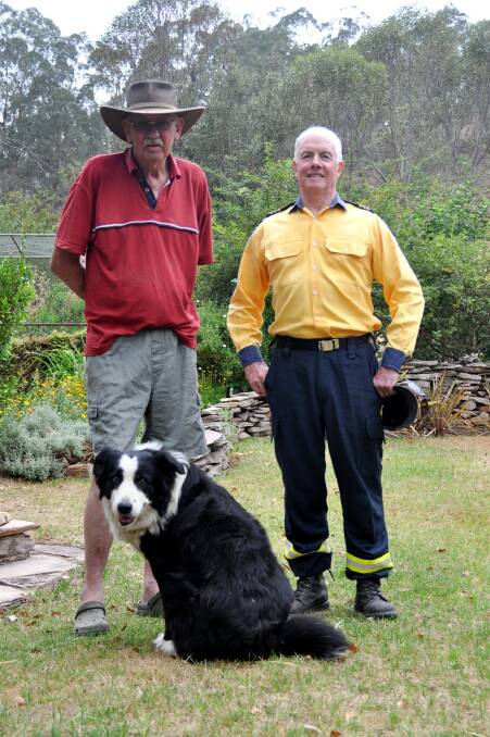 Mick Chalker stands in the garden at his Wombeyan Caves home of 49 years, spared from the fires, with dog Boof and Taralga Rural Fire Brigade Captain John Sullivan. Photo: Hannah Sparks